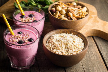 Glasses of berry smoothie with nuts, mint, blueberry, blackberry, raspberry, and yogurt on wooden table. Weight loss and diet concept. 