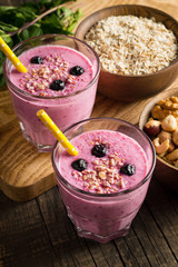 Glasses of berry smoothie with nuts, mint, blueberry, blackberry, raspberry, and yogurt on wooden table. Weight loss and diet concept. 