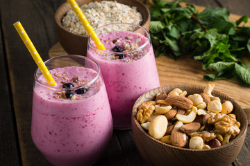 Glasses of berry smoothie with nuts, mint, blueberry, blackberry, raspberry, and yogurt on wooden table. Weight loss and diet concept. 