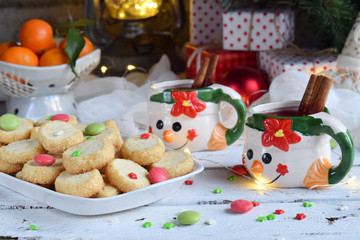 Christmas and new year holiday celebration concept background. Mug of mulled wine with spices, homemade nut cookie, shortbread, xmas tree decoration on wooden table.