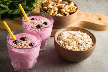Glasses of berry smoothie with nuts, mint, blueberry, blackberry, raspberry, and yogurt on wooden table. Weight loss and diet concept. 