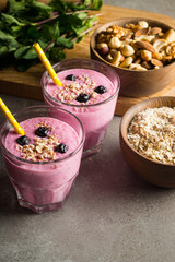Glasses of berry smoothie with nuts, mint, blueberry, blackberry, raspberry, and yogurt on wooden table. Weight loss and diet concept. 