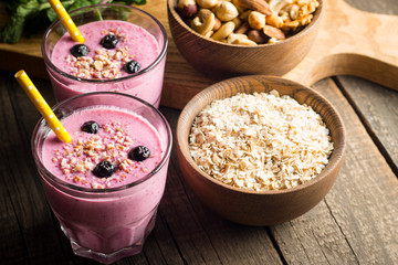Glasses of berry smoothie with nuts, mint, blueberry, blackberry, raspberry, and yogurt on wooden table. Weight loss and diet concept. 