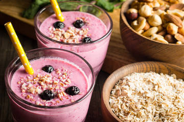 Glasses of berry smoothie with nuts, mint, blueberry, blackberry, raspberry, and yogurt on wooden table. Weight loss and diet concept. 