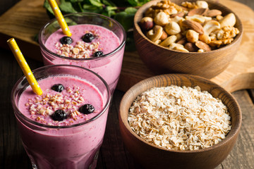 Glasses of berry smoothie with nuts, mint, blueberry, blackberry, raspberry, and yogurt on wooden table. Weight loss and diet concept. 