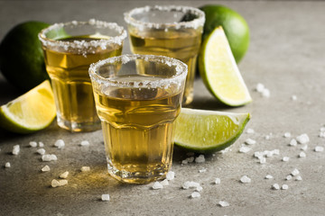Macro photo of shots of gold Mexican tequila with lime and salt on wooden rustic background. Alcoholic drink concept. selective focus.