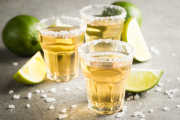 Macro photo of shots of gold Mexican tequila with lime and salt on wooden rustic background. Alcoholic drink concept. selective focus.