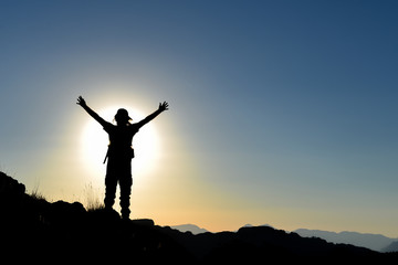 Fototapeta na wymiar successful mountaineer on top and sunset time