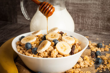 Healthy breakfast concept with oat flakes and fresh berries on rustic background. Food made of granola and muesli. Healthy banana smoothie with blackberries, honey and milk.