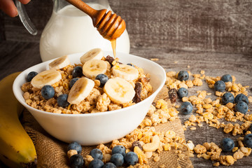 Healthy breakfast concept with oat flakes and fresh berries on rustic background. Food made of granola and muesli. Healthy banana smoothie with blackberries, honey and milk.