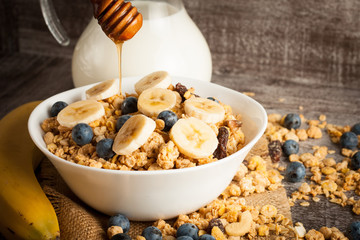 Healthy breakfast concept with oat flakes and fresh berries on rustic background. Food made of granola and muesli. Healthy banana smoothie with blackberries, honey and milk.