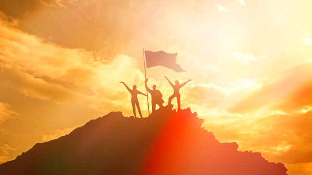 High achiever, silhouettes of three people holding on top of a mountain to raise their hands up. A man on top of a mountain. Conceptual design. Against a dramatic sky with clouds at sunset.