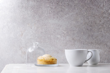 Sweet pear tartlet with cup of coffee espresso and jug of cream standing on white marble table with grey wall at background. Minimalist style. Copy space