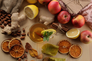 Autumn composition with hot tea, fruits and yellow leaves on a natural wooden table. view from above