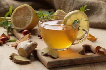 Autumn composition with hot tea with ginger and lemon on a natural wooden table.