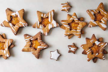 Homemade Christmas star shape sugar caramel cookies with frosting and orange citrus jam over white marble background. Flat lay, space. Sweet xmas or new year gift.