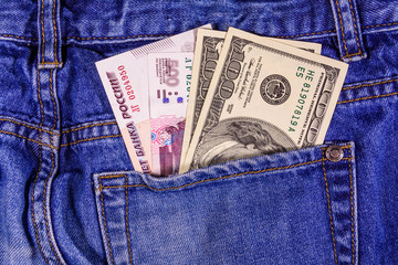 Different american and russian banknotes in a pocket of blue jeans