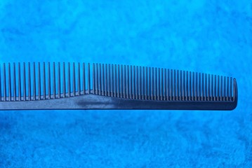 a black plastic comb rests on blue wool