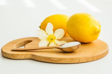two lemons, a wooden spoon with salt and a flower of narcissus on a wooden board 