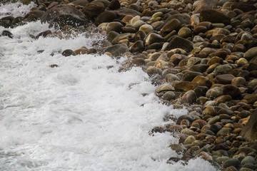 Rolling crashing waves on pebbles on a beach at Clarence Drive, between Kleinmond and Gordons Bay, Western Cape, South Africa.