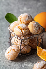 Homemade orange crinkle cookies with powdered sugar icing on gray background, vertical composition