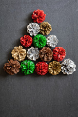Christmas tree made out od colourful pine cones on dark background, top view