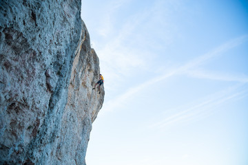 View of man without helmet hanging on a rope while rappelling and shows flying pirouettes in the air  © pablobenii