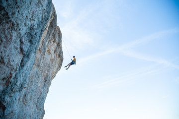View of man without helmet hanging on a rope while rappelling and shows flying pirouettes in the air  © pablobenii
