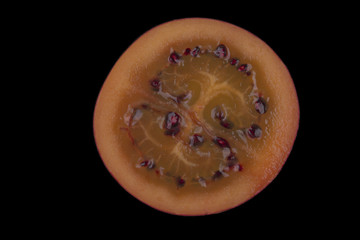 half of tamarillo isolated on black background