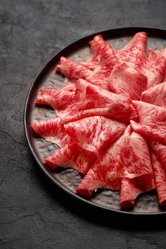 Japanese kobe beef sliced on ceramic plate on black background