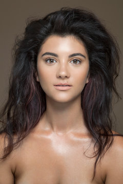 Portrait of a bare young woman with long, brown hair and natural make-up.