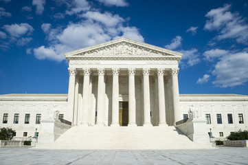 Supreme Court of the United States building in soft sunset light reflecting in the still water of a...