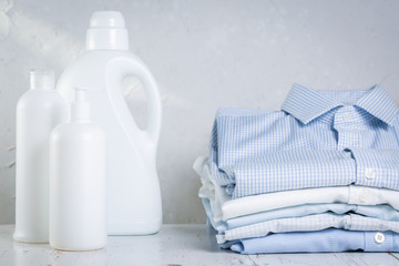 Fototapeta na wymiar Washing concept - pile of folded shirts with bottle of washing detergent, rustic background