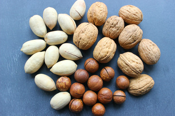 Assorted Walnuts, macadamia nuts and pecans close up on wooden table. Healthy food, cafe menu, vegan, vegetarianism, diet, vitamins, health
