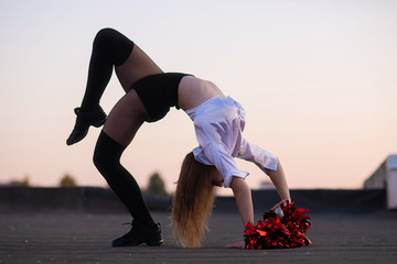 cheerleader with pompoms dancing outdoors on the roof at sunset