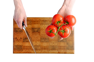 Woman hand holding tomato and knife on the kitchen cutting board isolated on white