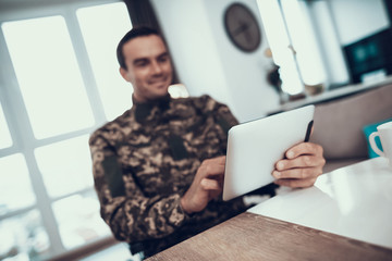 Smiling Military Man Uses Tablet in Living Room