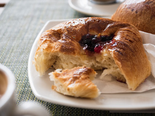Fresh muffin with jam and a cup of aromatic frothy coffee. Top view, close-up
