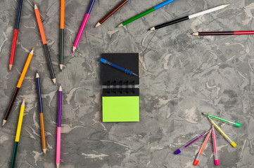 Blank paper notebook near stationery supplies on gray scratched concrete table. Top view. Business or education concept