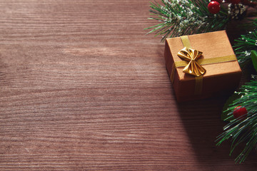 Fir tree branches, red berries and present box on wooden surface. Christmas and new year background.