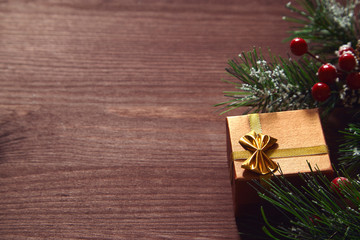 Fir tree branches, red berries and present box on wooden surface. Christmas and new year background.