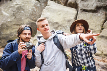 Handsome blonde traveller showing great place to his friend, his bearded friend ready to taking picture of the view, girl looking and admiring, travelling concept