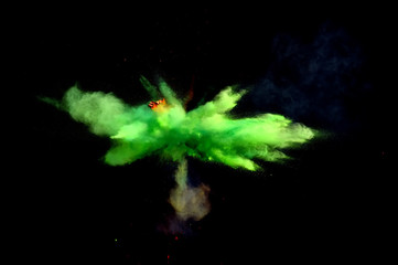 Colorful explosions of powder paint and flour combined  together explode in front of a black...