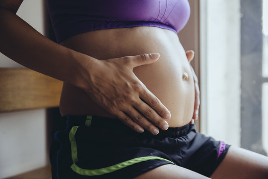 Sporty pregnant woman holding her belly
