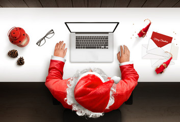 Santa Claus uses a laptop with isolated, blank screen for mockup, web site presentation. Top view...