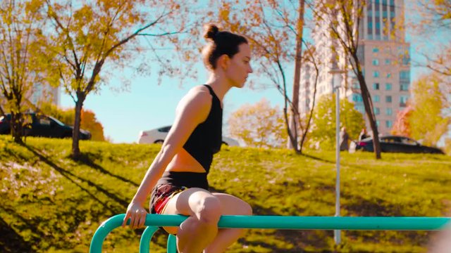 Female professional dancer performing choreographic exercises on parallel bars outdoors. Sunny day, golden autumn