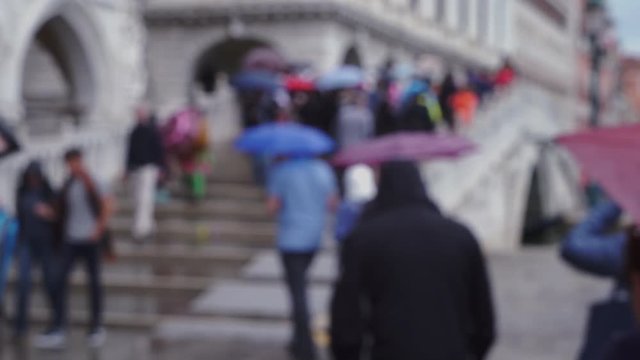 Blurred background of tourist crowd walking across bridge during thunderstorm Pedestrians in Venice Italy walking up bridge steps while holdings umbrellas 4k