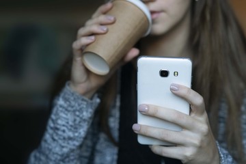 Woman holding a cup and looking at the phone