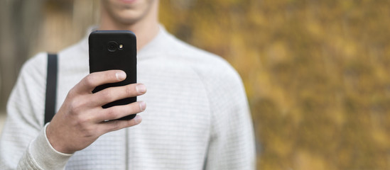 A man walks in the park and holds the phone in his hand