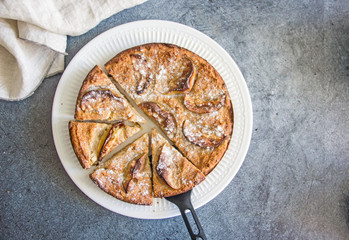 Top view of homemade apple pie on a white plate on a dark stone background. Next to a towel and a shovel for a cake. Copy space.